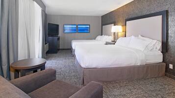 Habitación de hotel con dos camas, televisión, una mesita y un sofá.