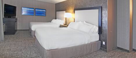 A hotel room with two beds, a television, and two framed pictures on the wall.