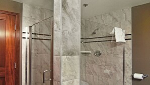 A modern bathroom with a glass-enclosed shower, marble tiles, a wooden door, and a towel rack. - Holiday Inn Express Hotel & Suites Calgary by IHG (Calgary)