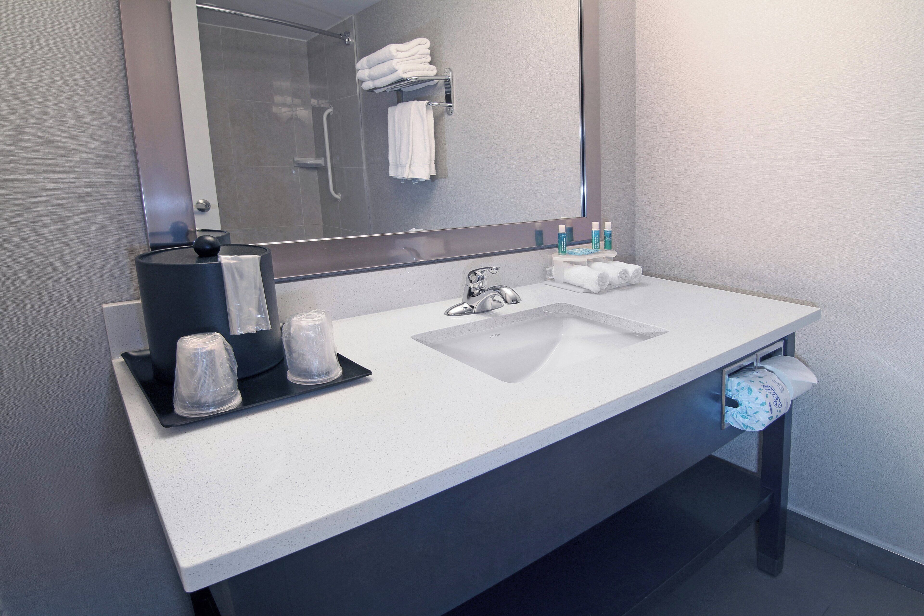Un baño moderno con un lavamanos blanco, un espejo grande y un perchero para toallas.