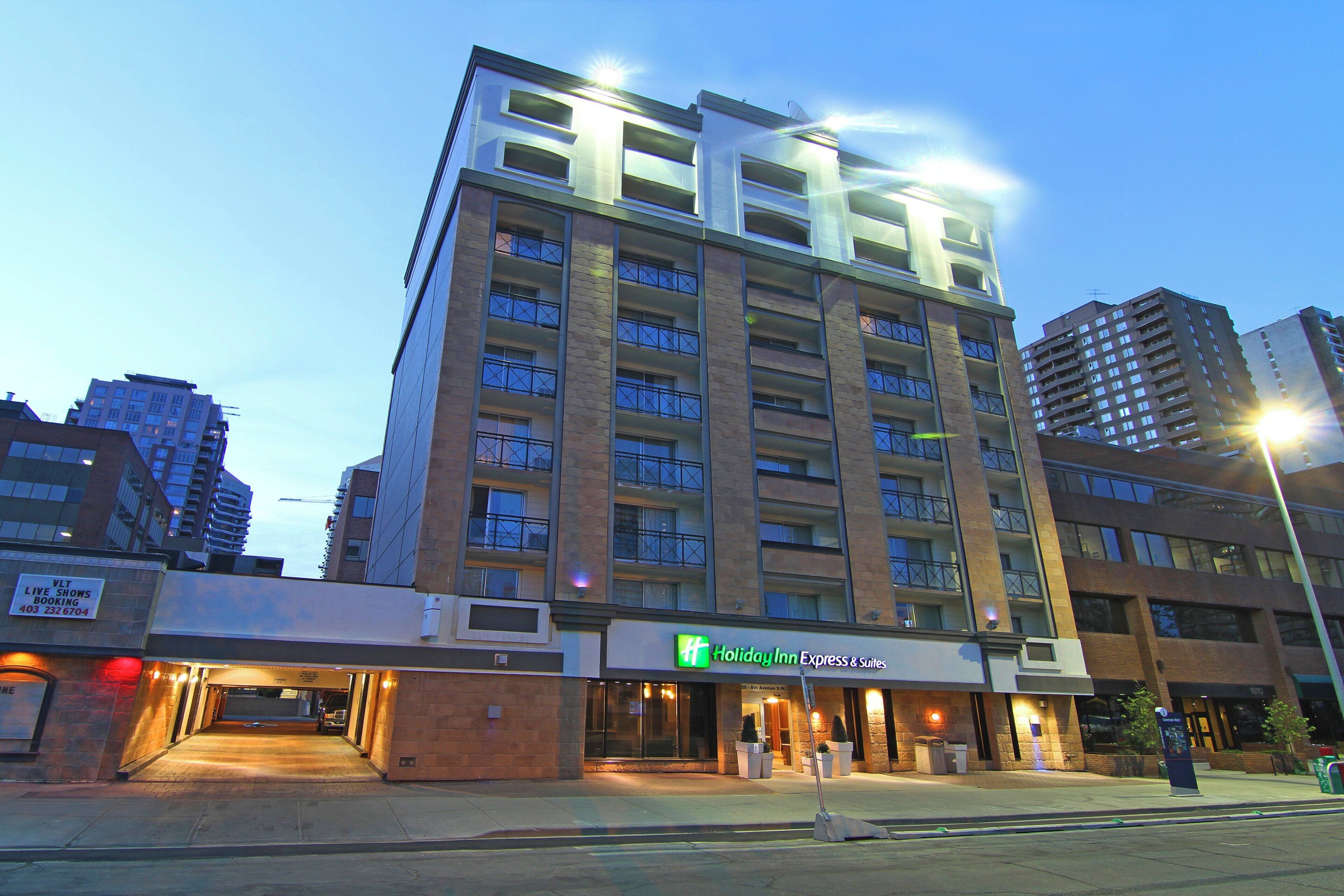 Een meerhoog hotel met een Holiday Inn Express & Suites bord, met een bakstenen gevel en meerdere balkons.