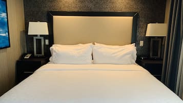 Un lit bien fait, recouvert d’une couvre-lit à motifs géométriques, avec deux lampes de chevet et un mur texturé de couleur sombre derrière la tête de lit.