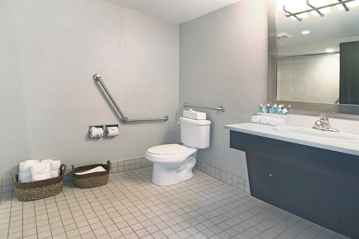 A bathroom with a white toilet, a sink with toiletries, and two baskets of towels.
