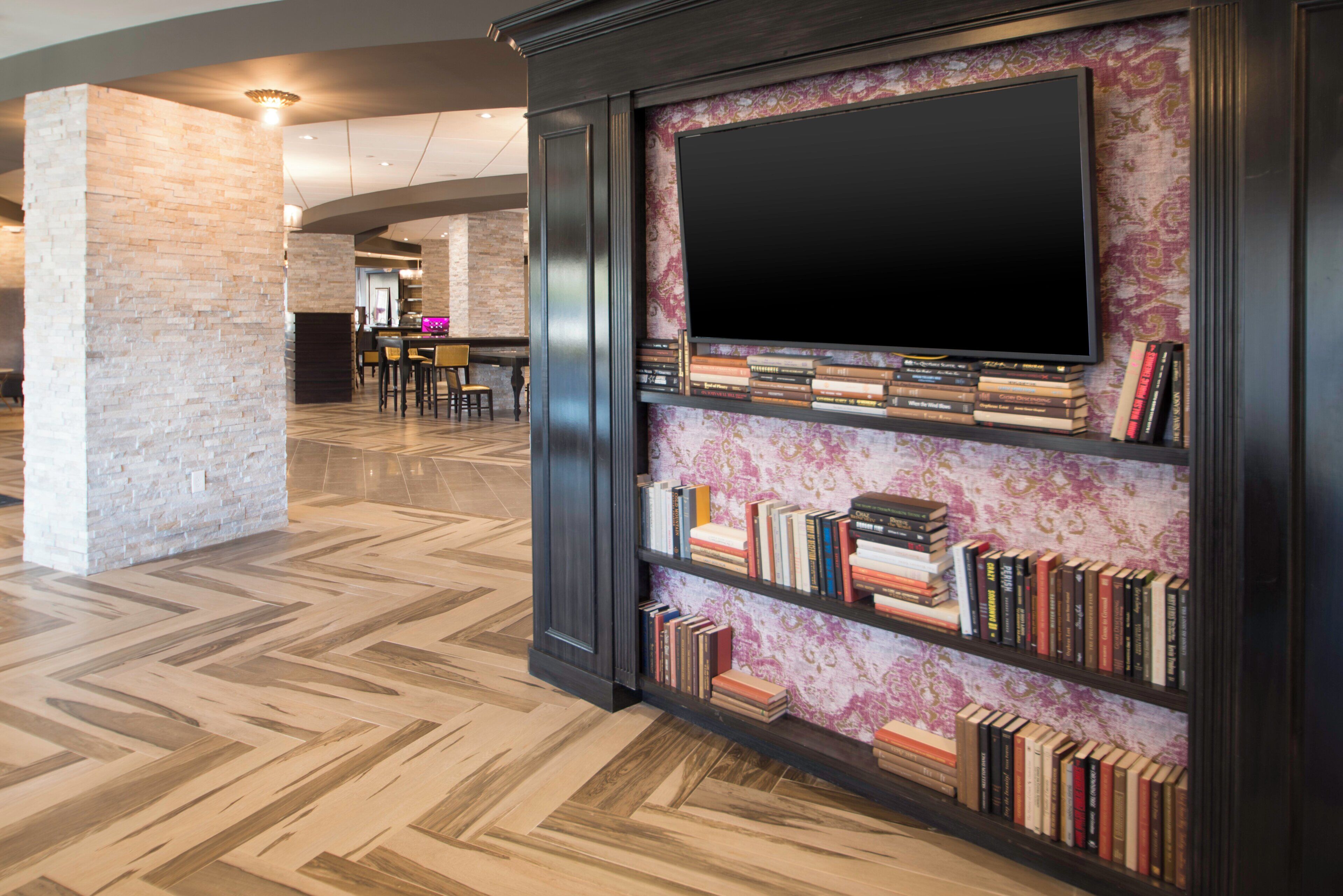 A modern interior with a flat-screen TV mounted on a wall, surrounded by bookshelves filled with books.