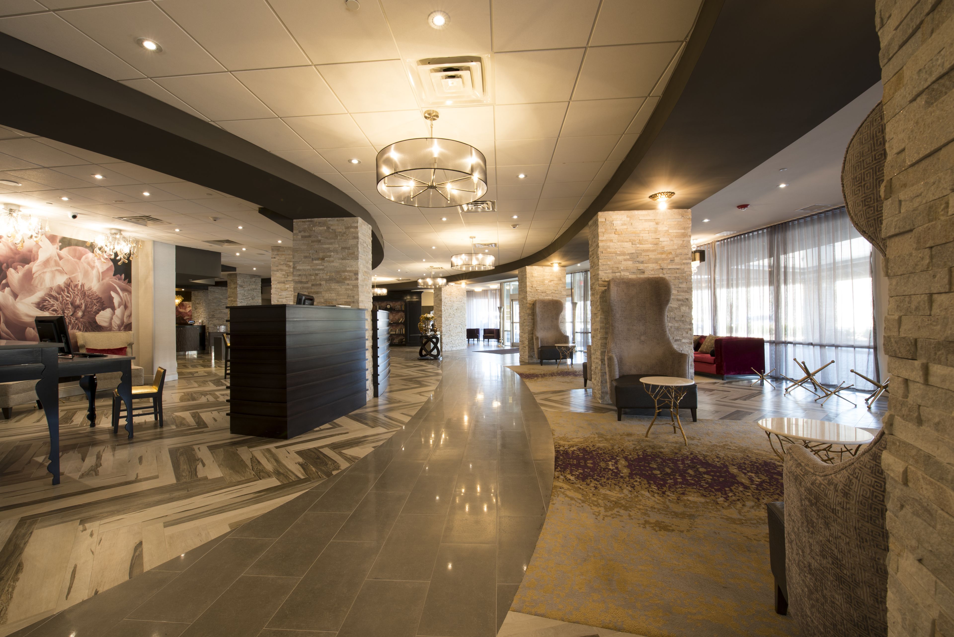 A spacious lobby with a curved ceiling, a reception desk, seating areas, and large windows.