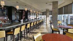 A bar area with a long counter, multiple chairs, and tables. - Crowne Plaza Saddle Brook by IHG (Saddle Brook)