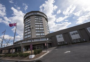 A hotel with a curved corner building, a parking lot, and a clear sky. - Crowne Plaza Saddle Brook by IHG (Saddle Brook)