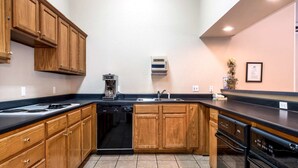 A kitchen with wooden cabinets, a dishwasher, a stove, and a sink. - Americas Best Value Inn Paris (Paris)