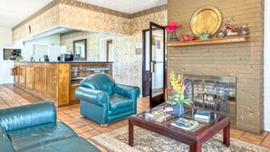 A lobby with a reception desk, a blue leather sofa, a coffee table with magazines, and a brick fireplace. - Americas Best Value Inn Paris (Paris)
