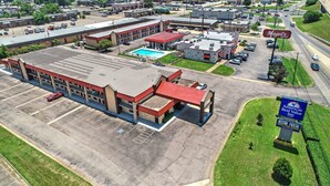 An industrial-style building with a red roof, a parking lot, and a sign for Magel's Grill.