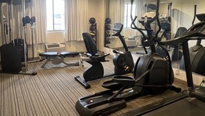 A hotel gym with cardio equipment, weight machines, and a mirrored wall.