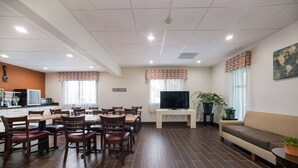 A dining area with wooden tables and chairs, a television, and a sofa.