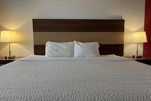 A neatly made bed with white bedding, two bedside lamps, and a wooden headboard.