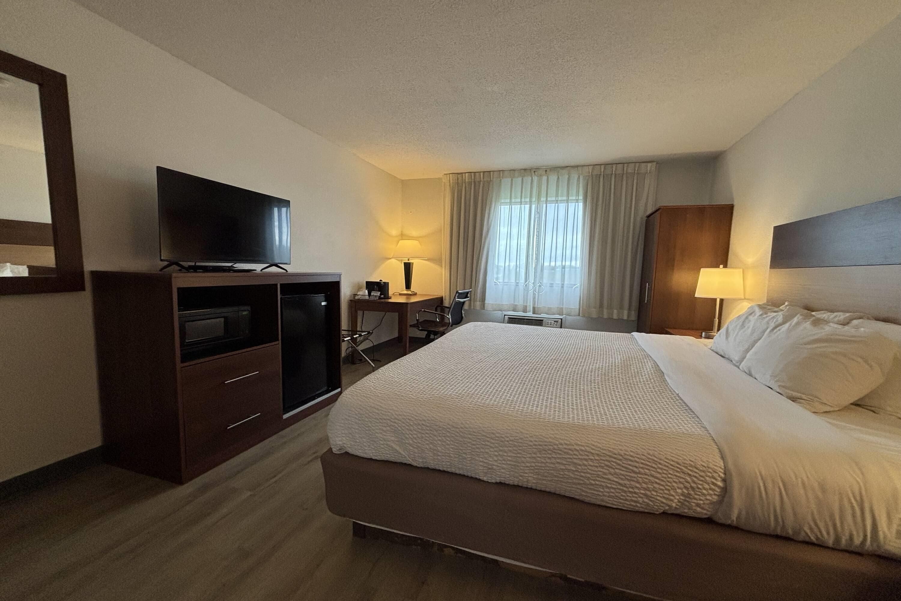 A hotel room with a bed, a TV, a desk, and a lamp.
