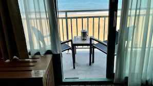 Ein Balkon mit Tisch und Stühlen mit Blick auf einen Strand und den Ozean.