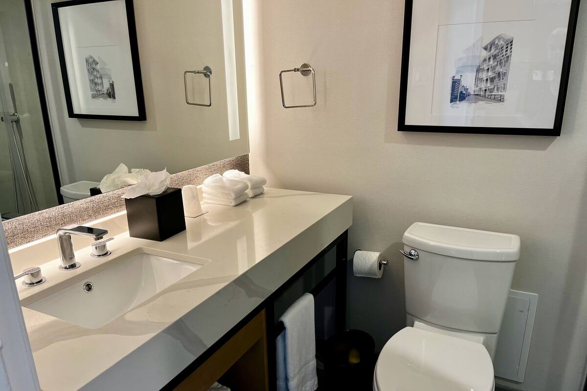 A modern bathroom with a white sink, a toilet, and framed artwork on the walls.