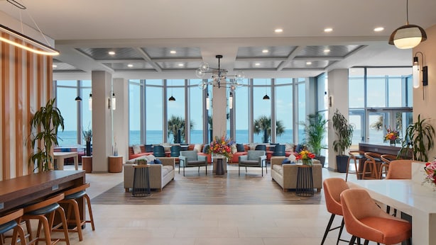Eine geräumige Lobby mit Barbereich, Sitzgelegenheiten und großen Fenstern mit Meerblick.