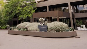 A high-rise hotel with multiple balconies, a landscaped entrance area, and a clear sky. - QT Canberra (Canberra)