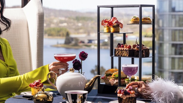 A table set for a tea service with a view of a lake and buildings in the background. - QT Canberra (Canberra)