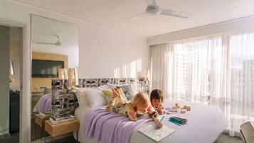 A hotel room with a bed, a bedside table, a mirror, a ceiling fan, and a window with curtains.
