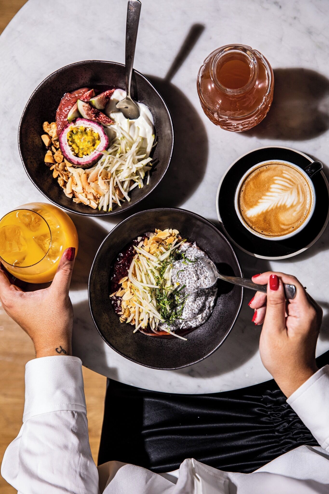 A table with two bowls of food, a glass of orange juice, and a cup of coffee.