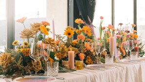 A table set for a meal with floral centerpieces, candles, and clear glassware. - QT Canberra (Canberra)
