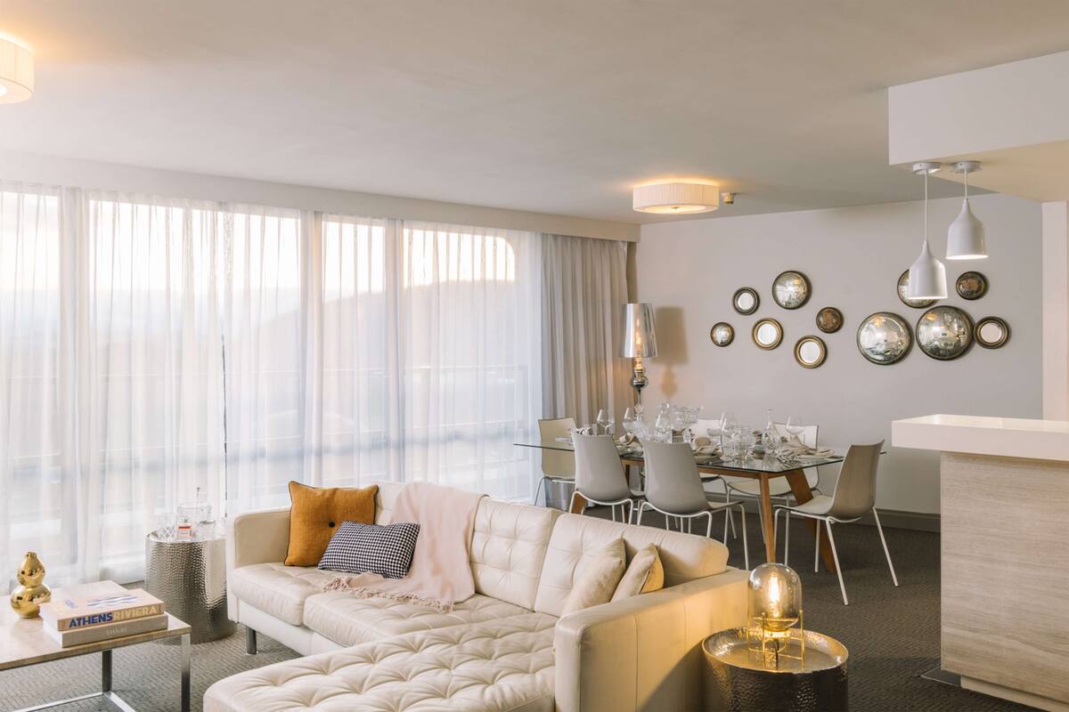 Uma sala de estar moderna com sofá, mesa de jantar e pratos decorativos na parede.