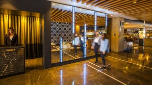 A modern lobby with a reception desk, a patterned wall, and a bar area. - QT Canberra (Canberra)