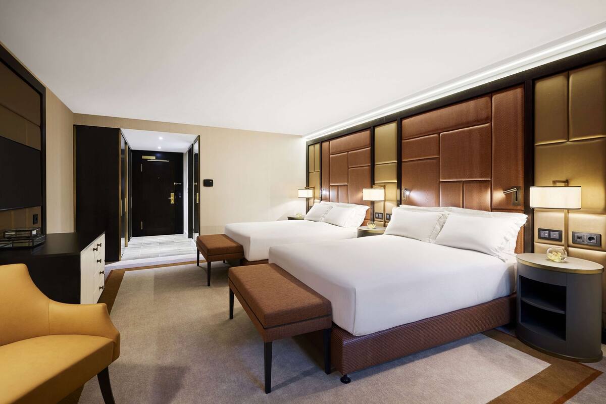 Une chambre d’hôtel avec deux lits, un bureau, une chaise et une télévision.