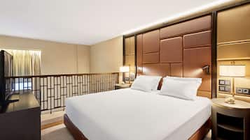 Una habitación de hotel con una cama grande, dos mesitas de noche, un escritorio y un televisor.
