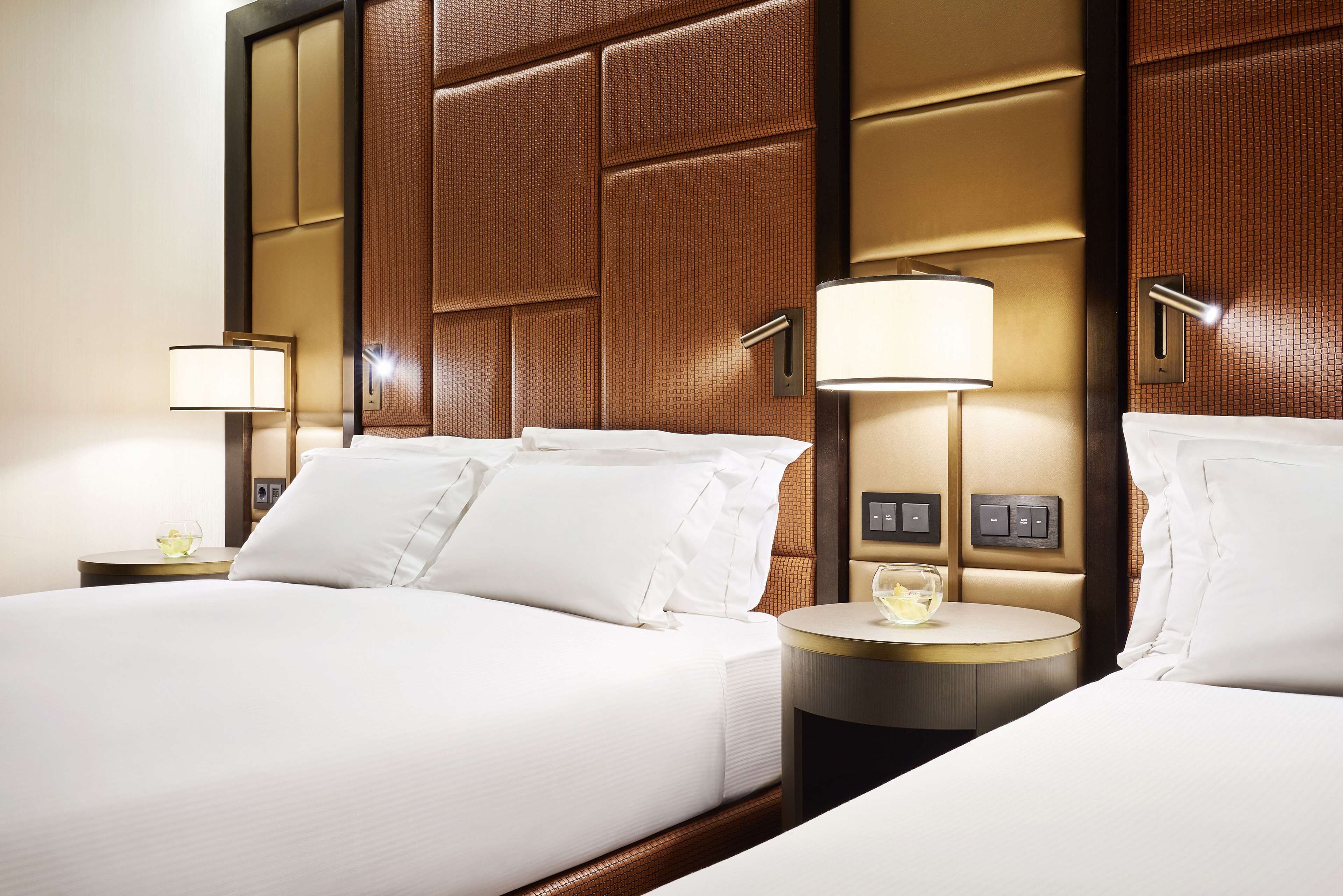 A hotel room with a large bed, two bedside tables, and a wall panel design.
