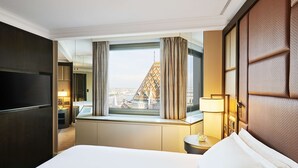 A hotel room with a bed, a nightstand, a lamp, and a view of a building with a distinctive tower. - Hilton Budapest (Budapest)
