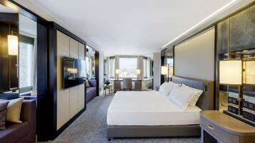 A modern hotel room with a large bed, a desk, a sofa, and a TV.