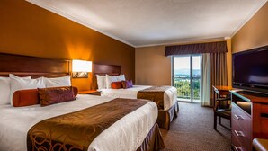 Une chambre d’hôtel avec deux lits, une télévision, un bureau et un balcon avec vue.