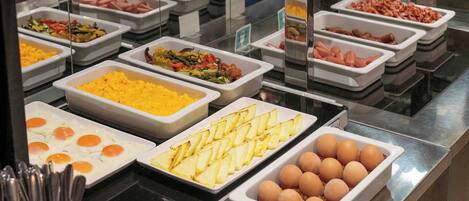 Un bufé con diversos alimentos, como huevos, papas y carnes.