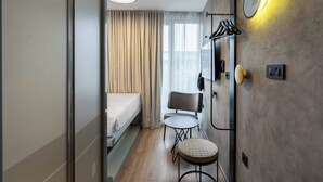 A compact hotel room with a bed, a small table, a chair, and a wall-mounted TV. - ibis Styles Ljubljana Centre (Ljubljana)