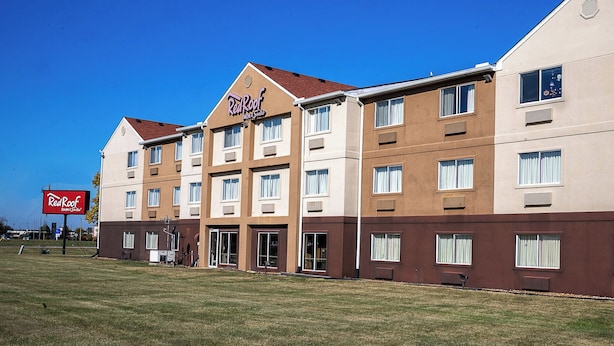 A Red Roof Inn & Suites hotel with a flat roof, multiple windows, and a grassy lawn in front.