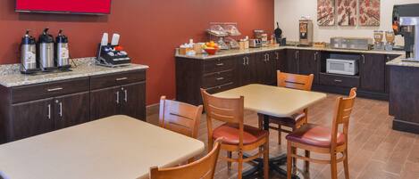 Cocina de hotel con comedor, que incluye una mesa con sillas, una estación de café y un microondas.