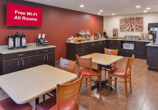 A hotel kitchen with a dining area, including a table with chairs, a coffee station, and a microwave. - Red Roof Inn & Suites Danville, IL (Danville)