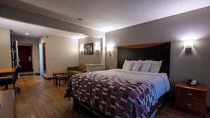 A hotel room with a large bed, a desk, a chair, and a small table.