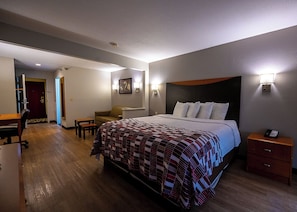 Una habitación de hotel con una cama grande, un escritorio, una silla y una mesita.