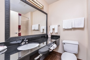 Un baño con lavamanos doble, inodoro y espejo grande.