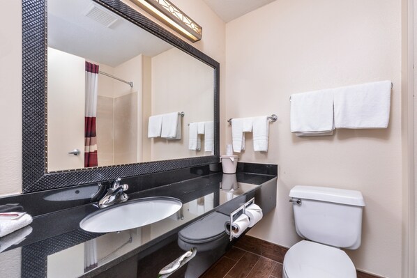 A bathroom with a double sink, a toilet, and a large mirror. - Red Roof Inn & Suites Danville, IL (Danville)