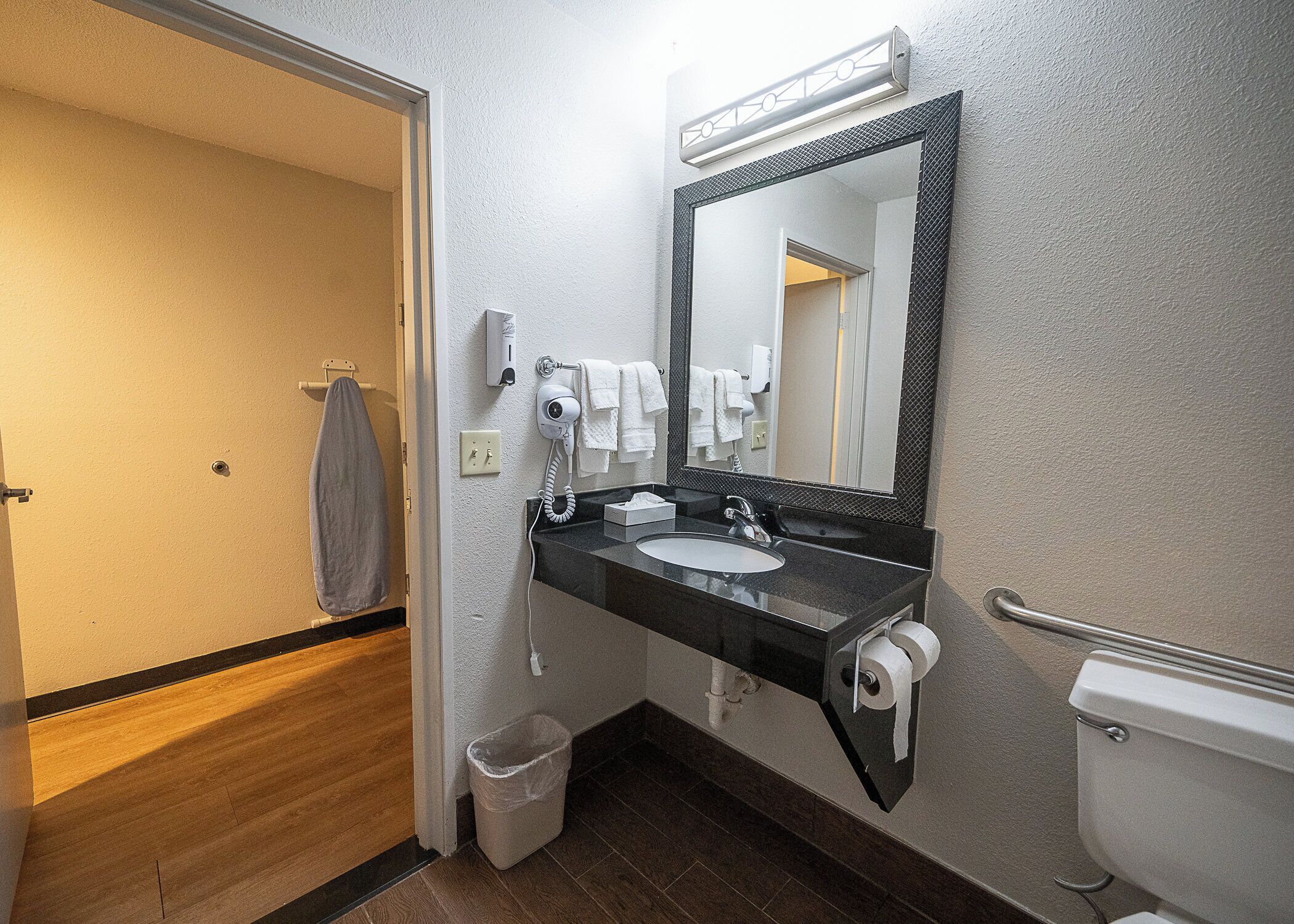A bathroom with a sink, mirror, towel rack, and toilet.