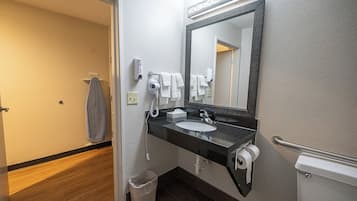 Ein Badezimmer mit Waschbecken, Spiegel, Handtuchhalter und Toilette.