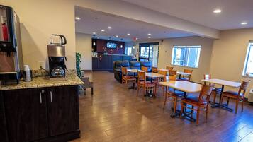 A spacious kitchen with a coffee machine, a refrigerator, and a dining area with wooden tables and chairs.