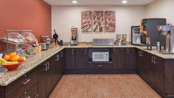 A kitchen with a microwave, coffee machine, and a fruit bowl.