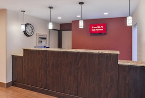 Un mostrador de recepción con un reloj, un panel de alarma contra incendios y un cartel que indica Wi-Fi gratuito en todas las habitaciones.