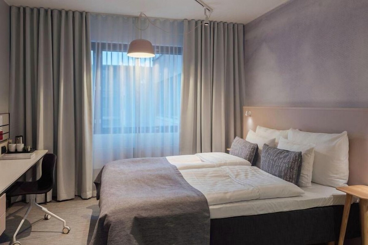 A hotel room with a bed, a desk, and a chair.