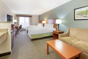 A hotel room with a bed, a sofa, a desk, and a TV.